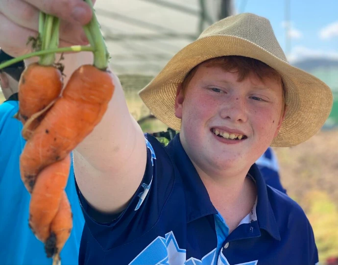 A young Homegrown Organics customer holding freshly picked carrots